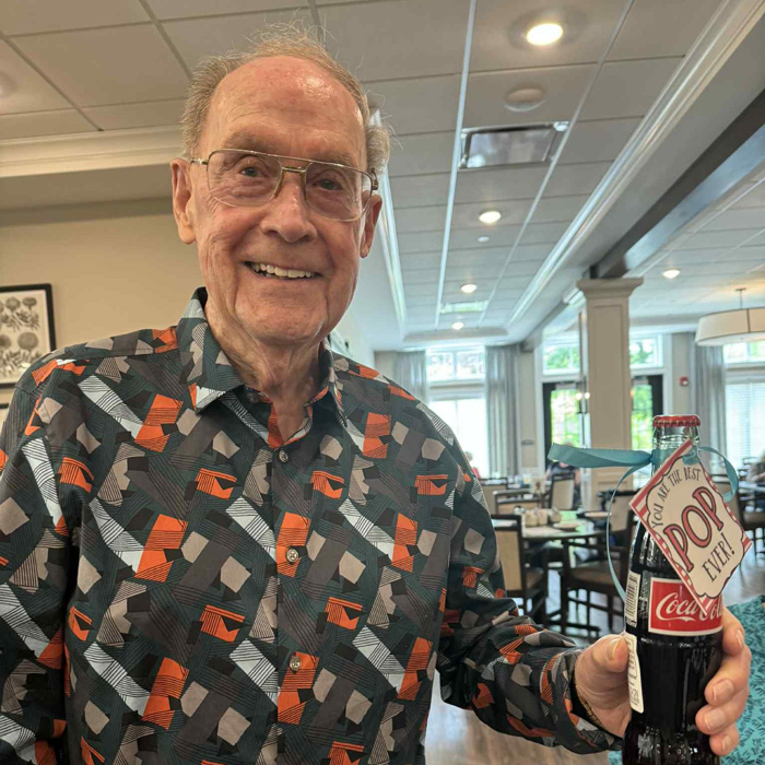 Senior man holding a vintage-style Coca-Cola bottle with a Father’s Day tag that reads “You’re the Best Pop Ever” at Vitalia North Royalton brunch celebration.