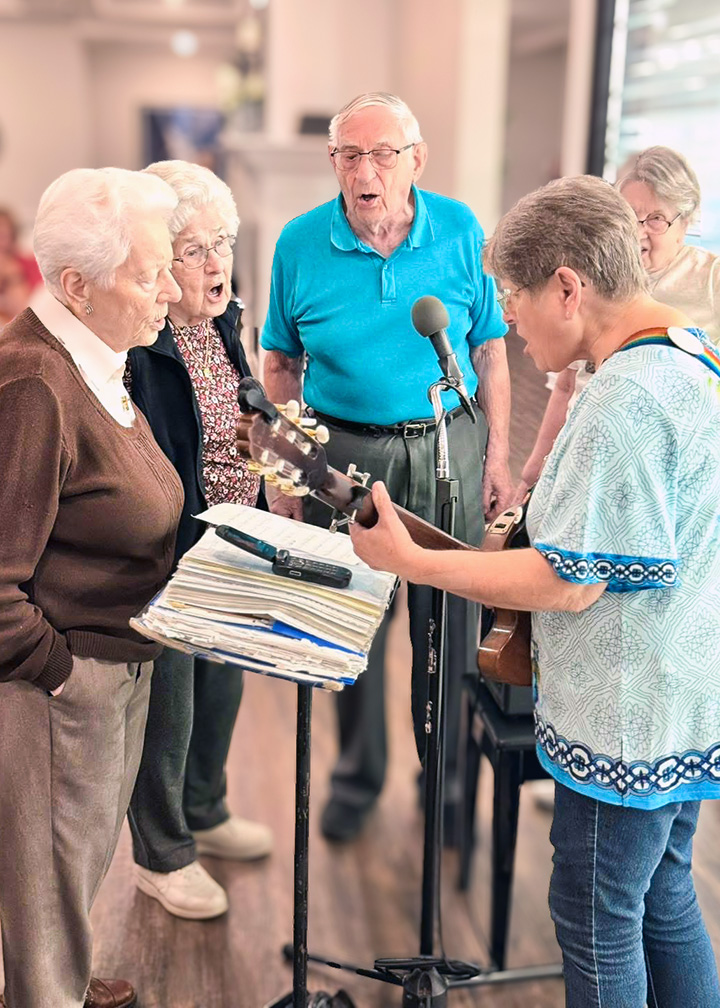 Seniors gather in a circle at Vitalia North Royalton, one playing the guitar while the group sings.