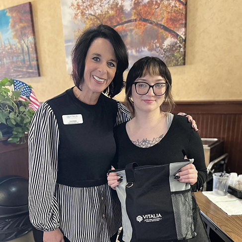 A team member from Vitalia North Royalton smiles alongside a local business owner holding a gift from the community.