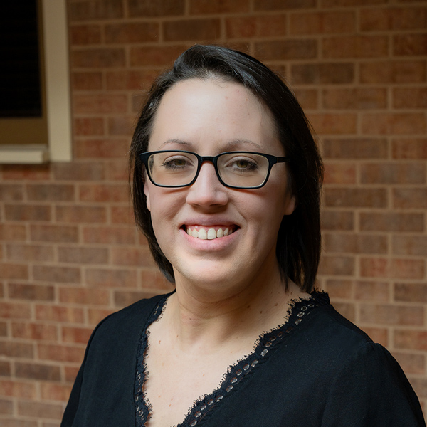 Stephanie “Steph” Galioto, Resident Services Director at Vitalia North Royalton, smiling in a professional headshot, wearing glasses and a black blouse, with a softly blurred brick background.